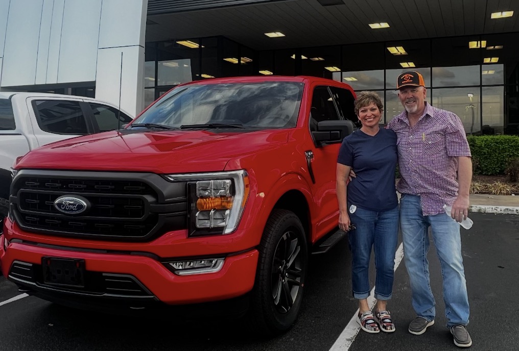 Couple with a bright red Ford F-150 on delivery day