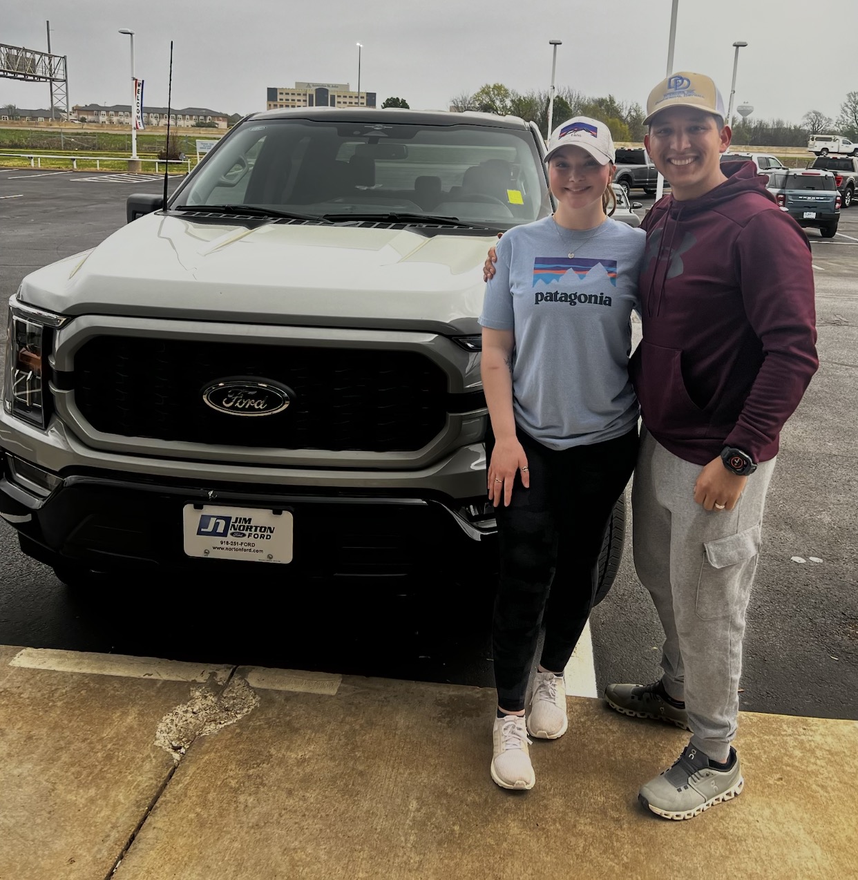 Young couple smiling in front of their new Ford pickup truck