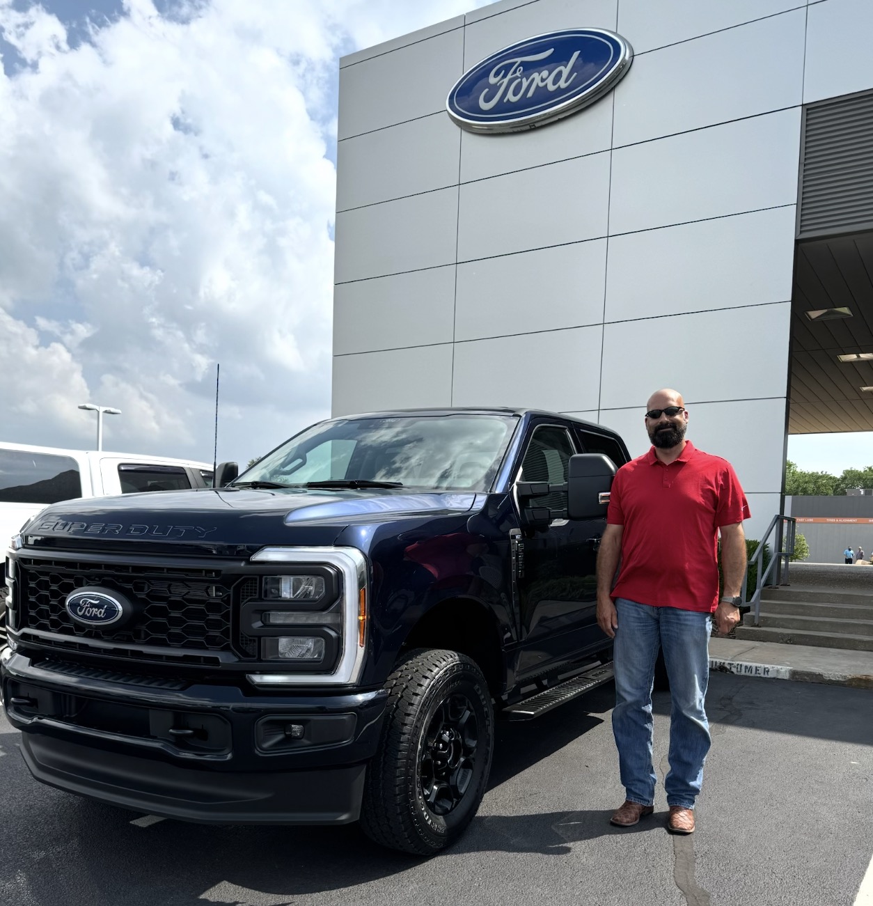 Customer beside a navy Ford Super Duty truck